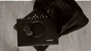 Musta Lenovo-läppäri ja kuulokkeet mustalla tuolilla, kuvattu ylhäältä.